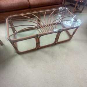 Rectangular rattan coffee table with sculptural curved base and glass top.