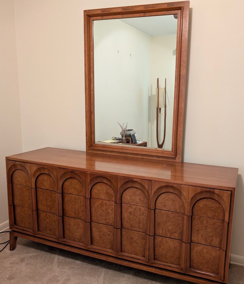 Wood dresser with arched panel drawer fronts and matching framed mirror.