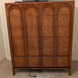 Wood highboy dresser with arched panel drawer fronts and warm brown finish.