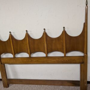 Vintage wood headboard with scalloped arch design and decorative finials.