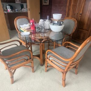 Round rattan dining table with sculptural base and glass top.