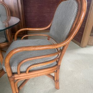 Set of four rattan dining chairs with curved arms and upholstered seats and backs.