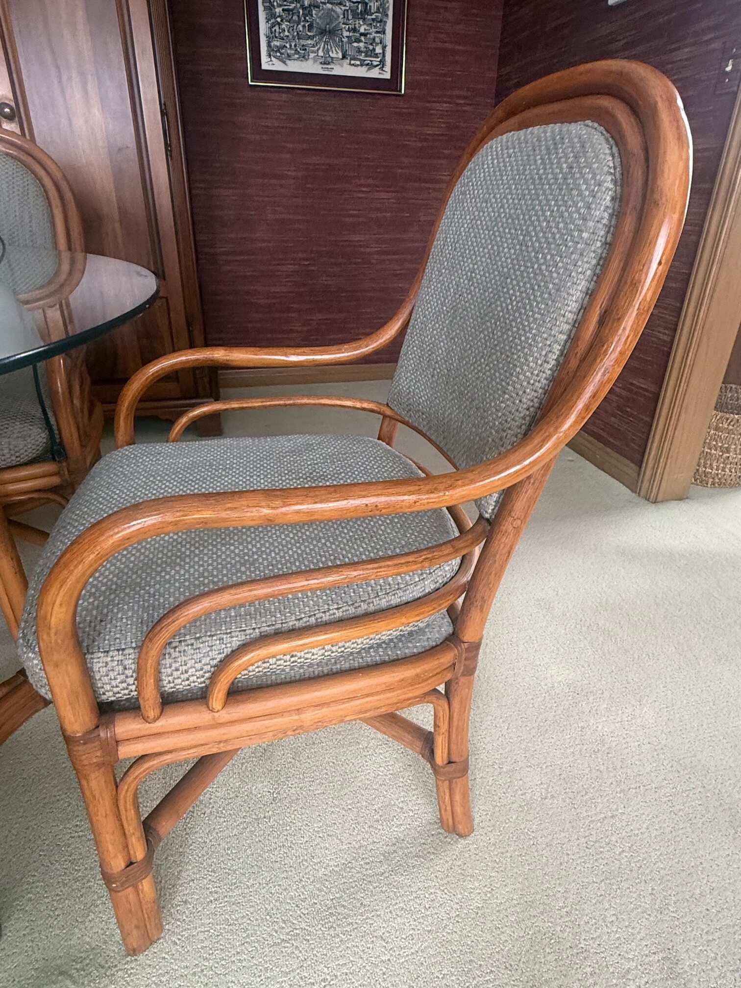 Set of four rattan dining chairs with curved arms and upholstered seats and backs.