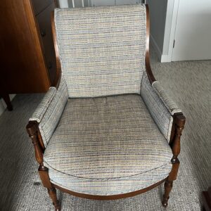 Wood framed upholstered armchair with multicolor woven fabric and curved arms.