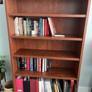 Medium-tone wood bookcase with four shelves and open back panel.