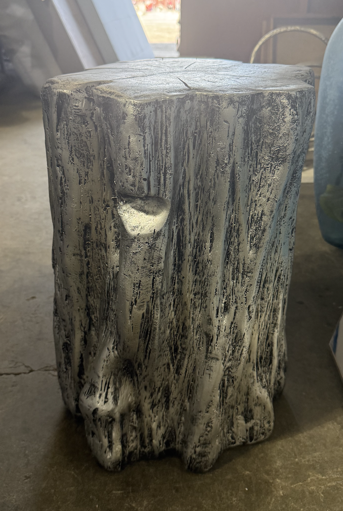 Gray faux tree stump accent table with textured sculpted surface and flat top.