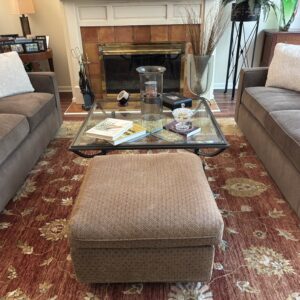 Rectangular glass top coffee table with dark metal frame and lower support detail.