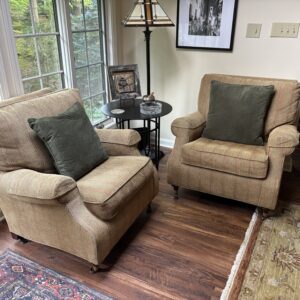 Pair of neutral striped upholstered armchairs with rolled arms and cushioned seats.