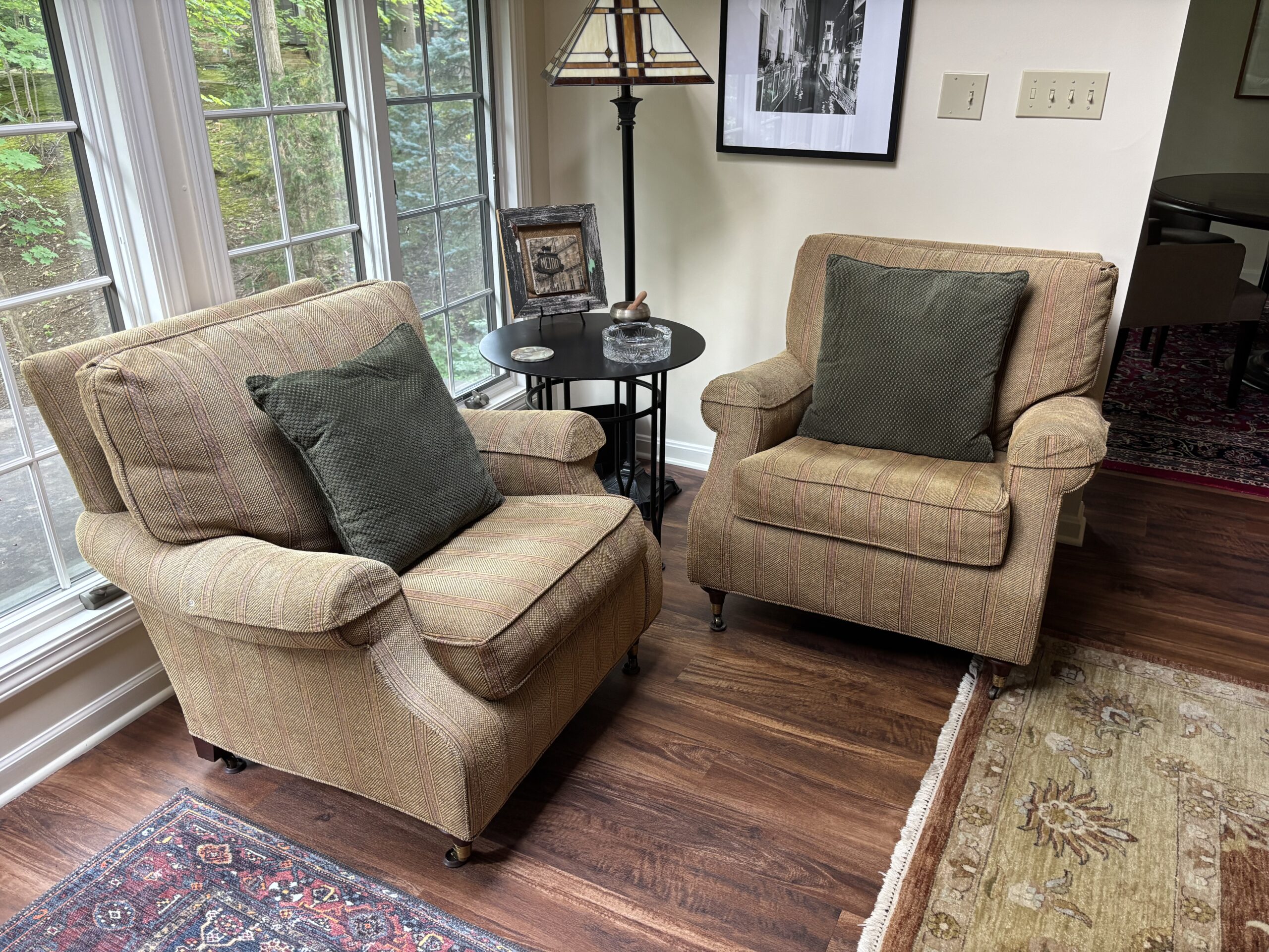 Pair of neutral striped upholstered armchairs with rolled arms and cushioned seats.