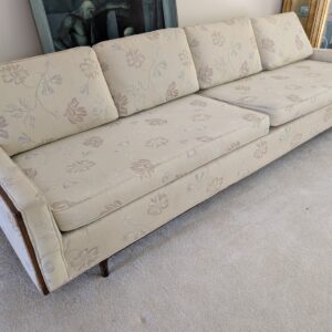 Vintage neutral floral upholstered sofa with tailored cushions and wood trim detail.