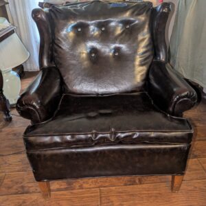 Black vinyl armchair with tufted back and rolled arms