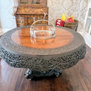 Vintage round wood table with intricately carved ornate base and smooth top