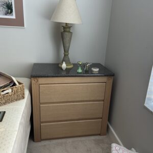 Pair of light wood three-drawer nightstands with stone tops.