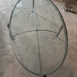 Oval glass coffee table with silver metal frame and crossbar base.