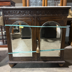Vintage wood cabinet with mirrored doors, carved details, and marble top