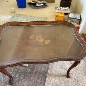 Wood coffee table with glass top and carved legs.